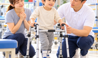 痙性両麻痺の子どもが歩行器を使って理学療法士と歩行練習をする様子