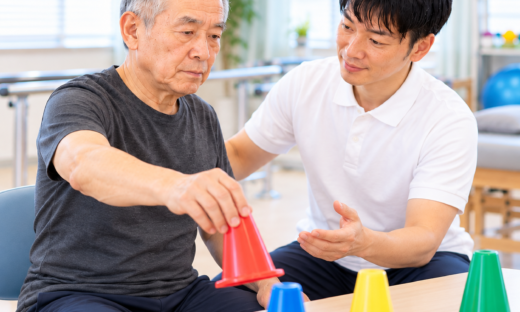脳腫瘍治療後の患者がセラピストと一緒に上肢の協調運動トレーニングを行う様子