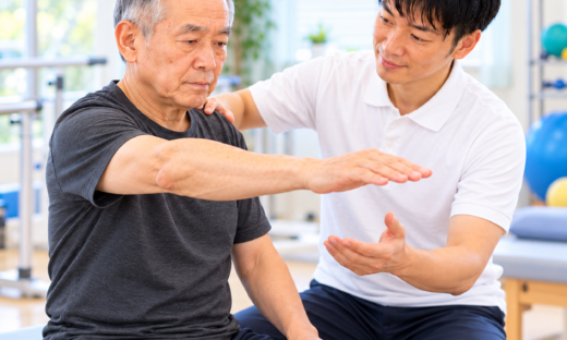肩関節不安定症のリハビリで理学療法士が患者の肩甲骨を支えながら腕の挙上運動を指導する様子