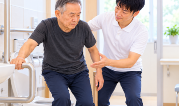 脳卒中後の尿失禁・排尿障害に対するリハビリテーションとして、理学療法士が高齢患者のトイレ移乗動作を支援している様子